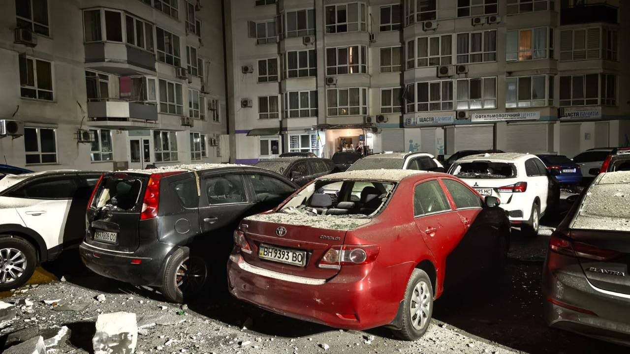 Автомобілі, засипані уламками, у дворі житлового будинку після обстрілу