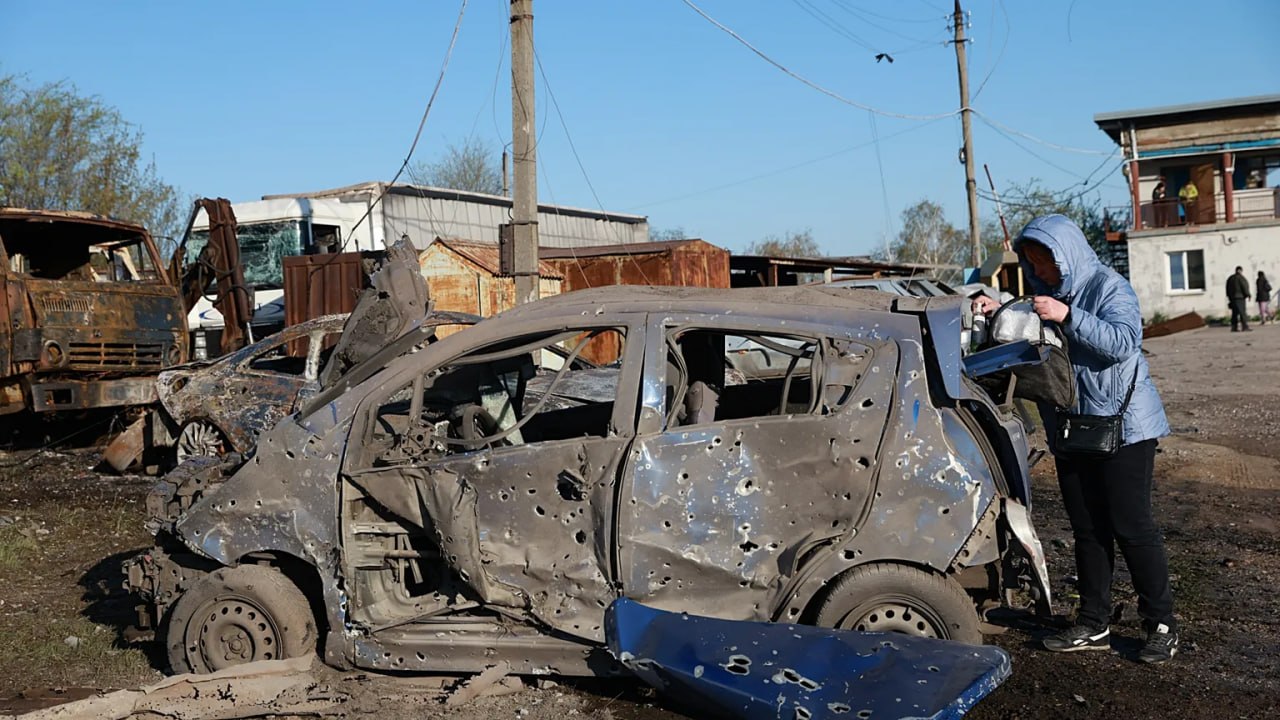 Жінка біля свого автомобіля, посіченого осколками